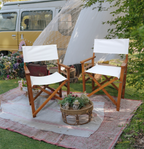 Front view of natural wooden folding director chair with canvas seat, standing on grass