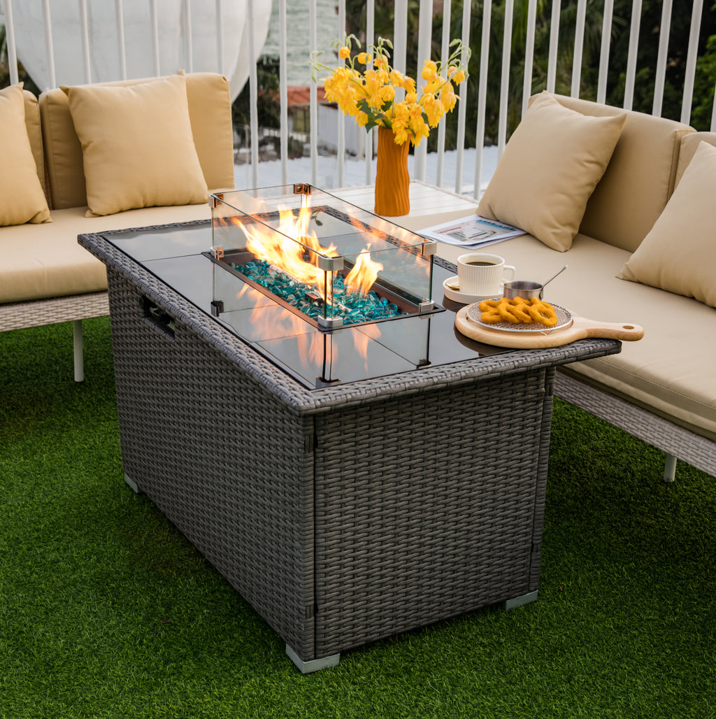 Glass wind guard installed around a rectangular fire table in outdoor setting