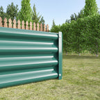 Green metal raised garden bed installed in soil with plants