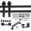 Front view of black sliding barn door hardware kit showing rail, hangers, and accessories laid out on a clean surface
