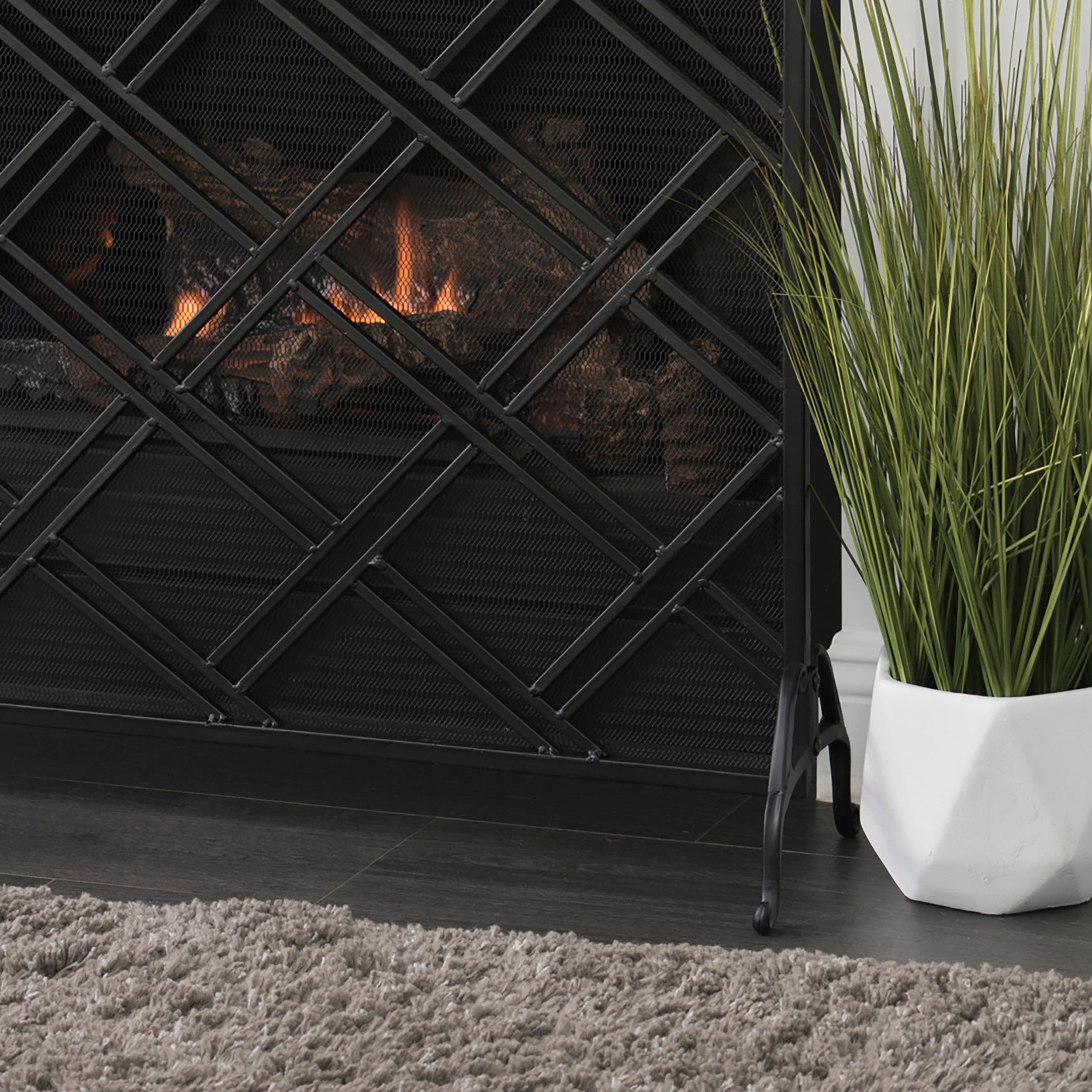 Close-up of black iron scrollwork and mesh pattern on fireplace fire screen