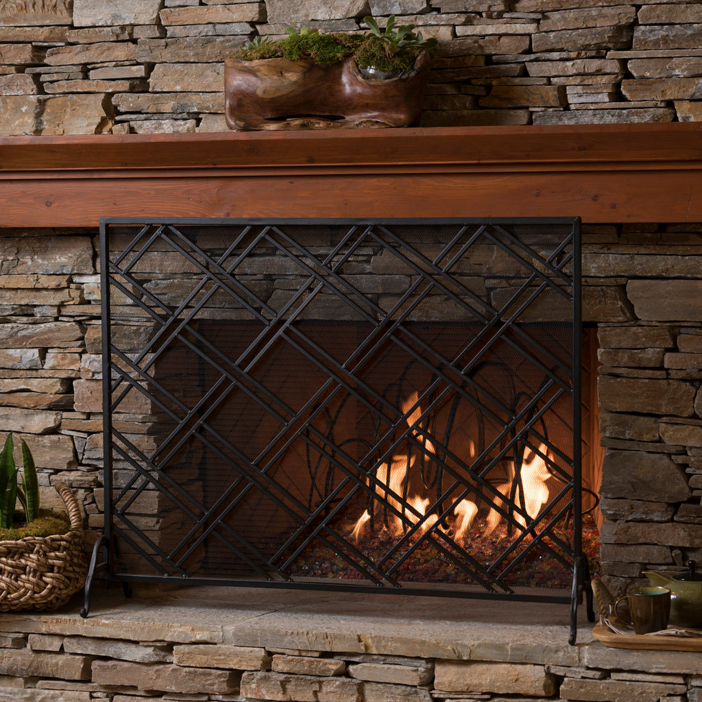 Black iron fire screen placed in front of a fireplace in a living room setting