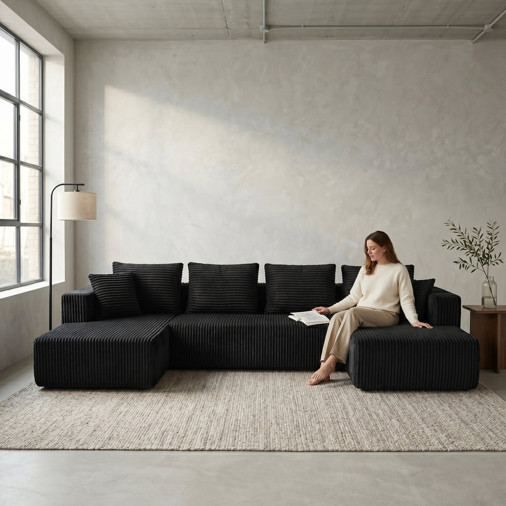 Front view of black U-shaped corduroy sectional sofa with double chaise in a living room setting