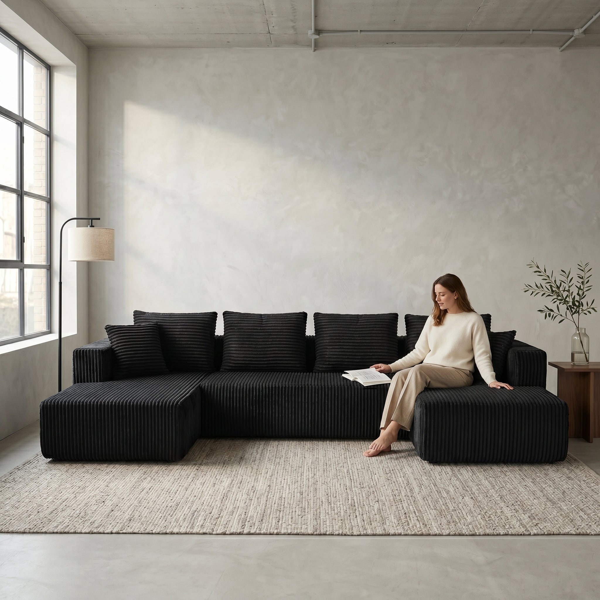 Front view of black U-shaped corduroy sectional sofa with double chaise in a living room setting