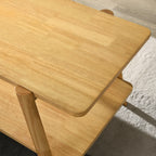 Metz end table at an angle showing sculptural curves, rubberwood legs, and shelf space